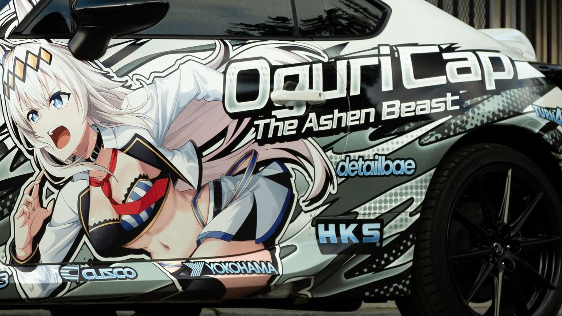 Toyota GR86 Oguri Cap itasha wrap front quarter view — white with halftone graphics and StyleUp branding